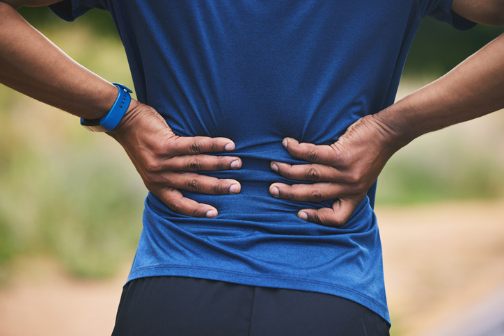 Back pain, fitness and hands of man in park after workout, exercise and training or running outdoors. Medical emergency, health and closeup of male person with muscle strain, injury or hurt in nature Lower Back (Lumbar) in Orange County